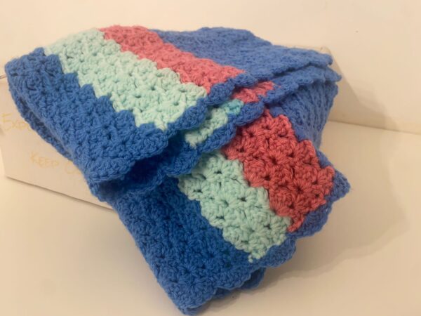 The Layla crochet blanket, made with deep blue, lime green and bright orange wools, in a unique crochet pattern.